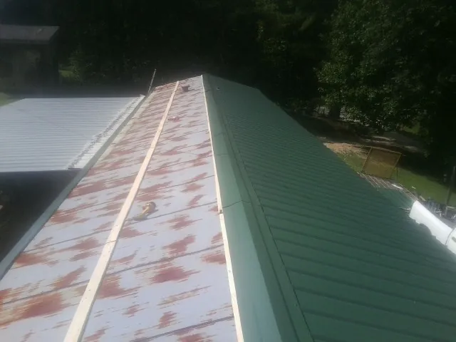 Old rusted panels beside newly installed green metal roofing — Wind Damage Roof Repair by Roofing Brothers in East Texas