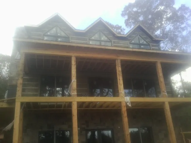 Dormers and porch framing on a large log home under construction — Roof Coating work by our crew in East Texas