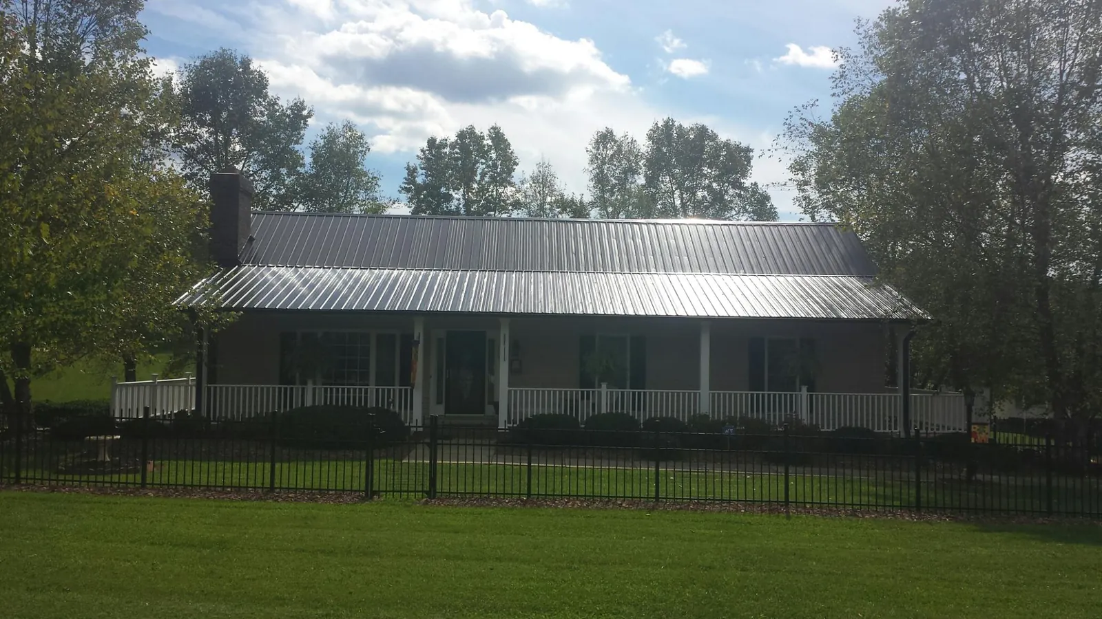Gray metal roof on a brick ranch with a full width front porch — Gutter Guard Installation work by our crew in East Texas