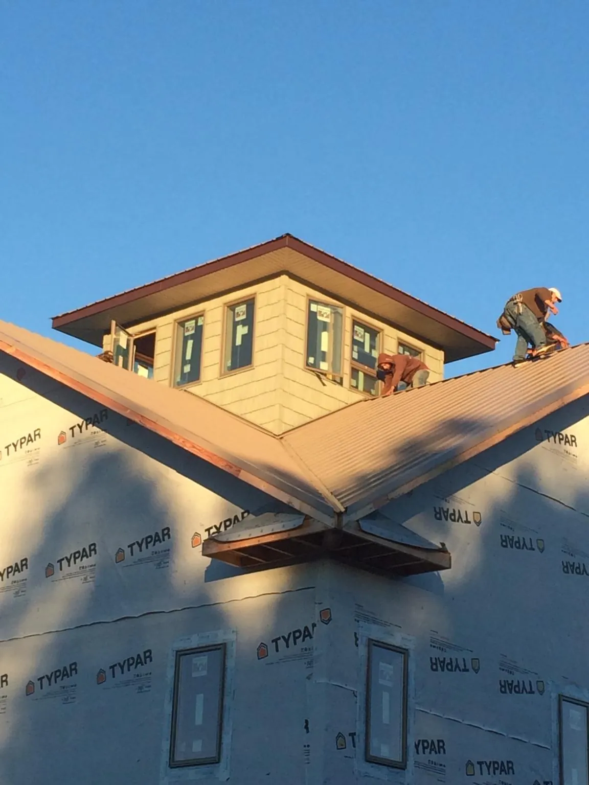 Roofers working around a rooftop cupola on a new metal roof at sunset — Roof Waterproofing in East Texas by Roofing Brothers